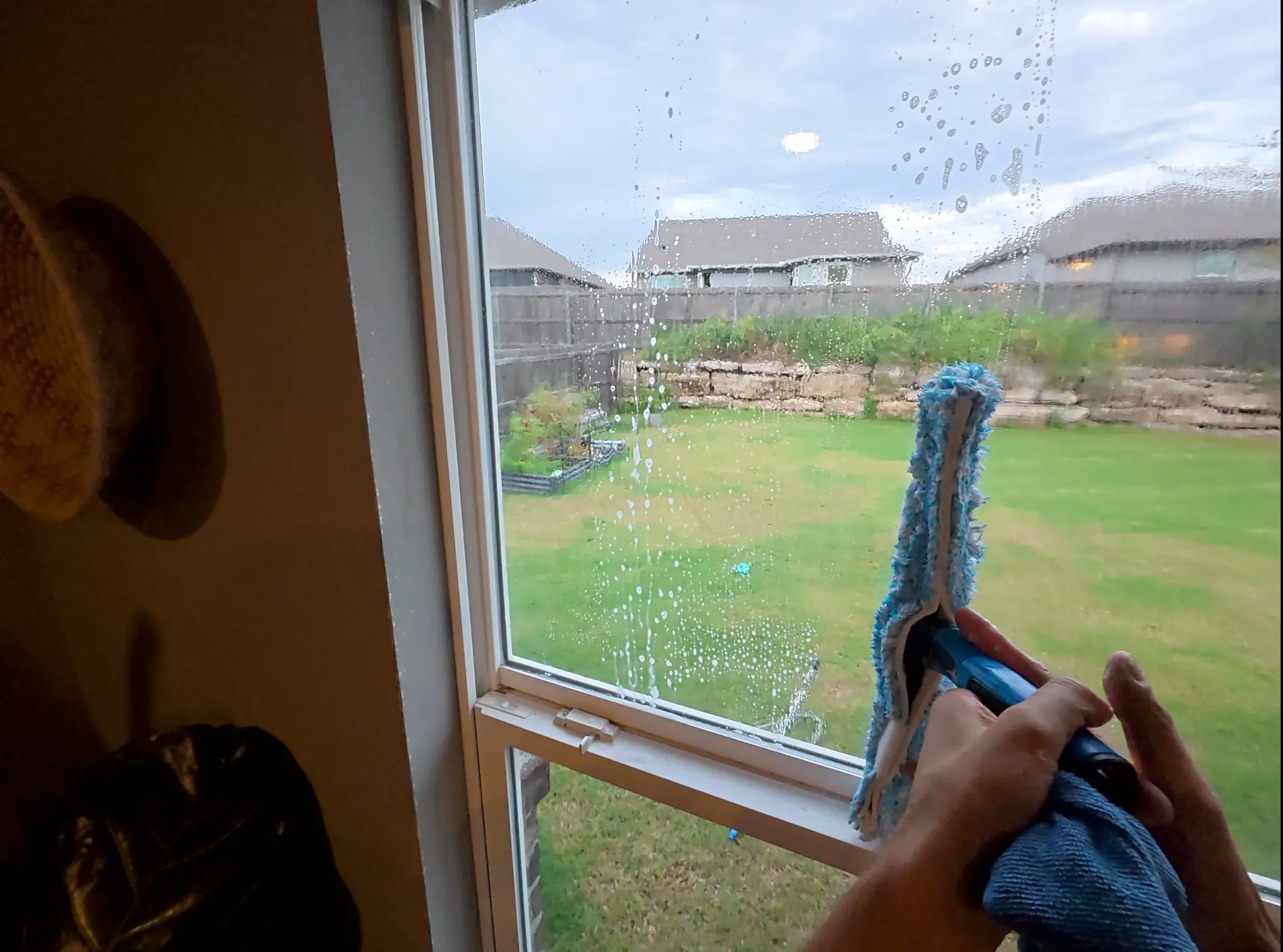 Cleaning the interior of a large window overlooking a backyard